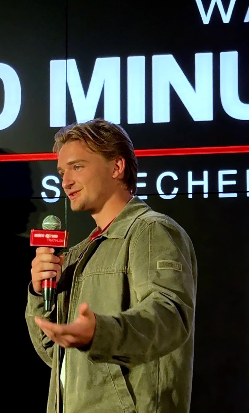 Jan Panser spricht mit Mikrofon auf der Bühne bei der Filmpremiere des Austria eXtreme Triathlon